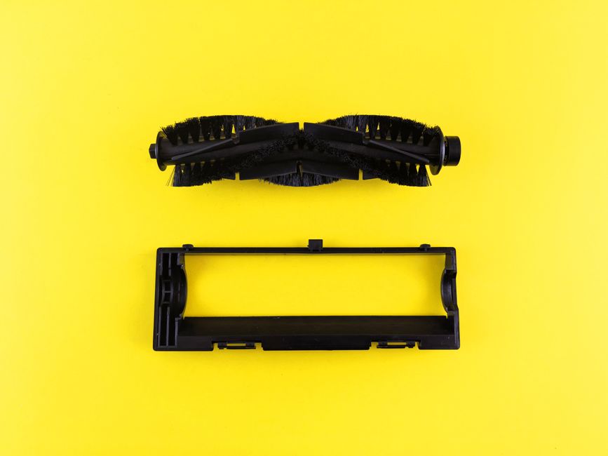 A set of two black vacuum cleaner brush attachments are displayed on a bright yellow background. The larger brush, positioned at the top, has dense black bristles arranged in a curved, cylindrical for